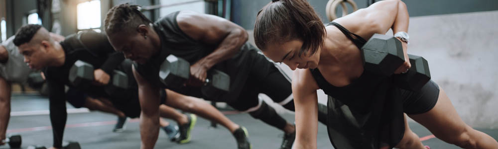 Men and women in a group fitness dumbbell row workout in a class